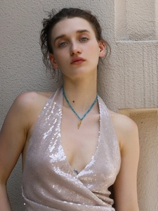 Detail of turquoise beaded necklace with golden leaf pendant worn by a model