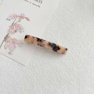 Close-up of a tortoiseshell acetate hair clip with spring fastener on textured background
