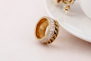 Macro detail of gold-plated spinner ring with baguette zircon stones and cuban chain texture