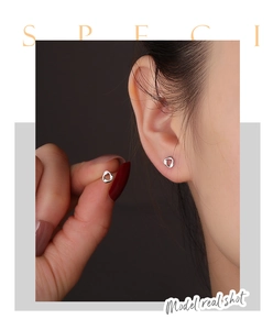 Close-up of minimalist sterling silver twisted stud earring on female model ear