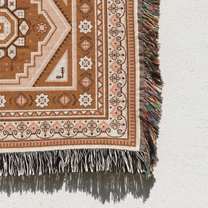Close-up of bohemian woven camping blanket featuring ethnic patterns and colorful tassels