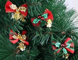 Close-up of four festive Christmas bows with golden bells on green pine branches