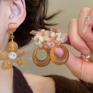 Close-up of resin flower earrings in amber and white with sparkling crystal accents