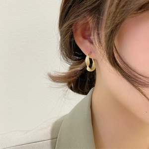 Elegant gold twisted hoop earrings worn by model showing a minimalist metallic design