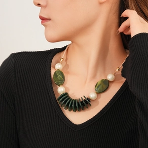 Detail of vintage layered necklace with green resin beads and pearls on model