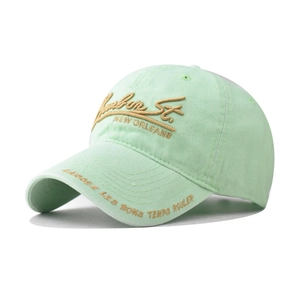 Detailed embroidery on a washed mint green cotton baseball cap with vintage texture