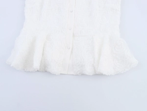 Detail of white blouse featuring 3D rose flower texture and ruffled hem with buttons