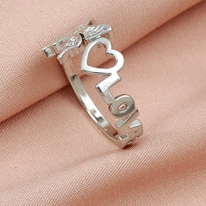 Macro shot of silver ring with hollow LOVE lettering and detailed wing relief