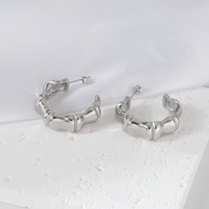 Silver stainless steel C-shaped earrings with bamboo texture on textured white background