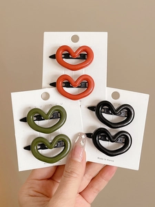 Three pairs of hollow heart hair clips in orange, green and black on white cards