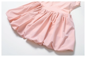 Detail of light pink athletic dress featuring elastic pleated hem and soft fabric