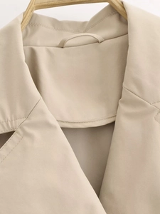 Macro view of khaki trench coat collar and neck loop detail on a wooden hanger