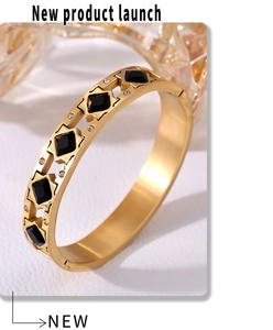 Detalle de brazalete bañado en oro con piedras romboidales negras y circonitas blancas
