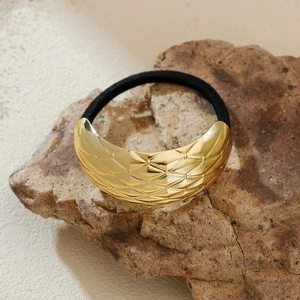 Golden crescent metal ponytail cuff with diamond texture on a natural stone base