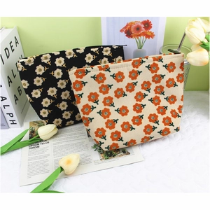 Close-up of floral corduroy makeup bags in black and beige with vintage flower prints