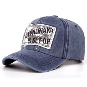 Detail of navy blue washed baseball cap with frayed brim and square embroidered patch