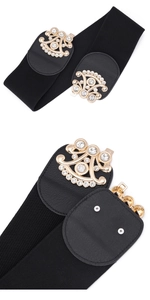 Detail of black elastic waist belt with a fan-shaped golden rhinestone buckle on white background