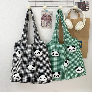 Detail of checkered canvas tote bag with plush panda decorations and sturdy handles