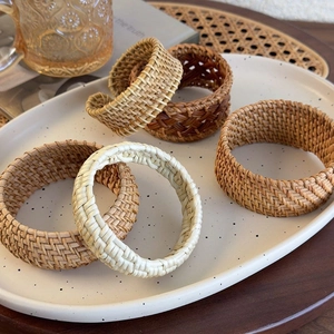Ethic hand-woven rattan open cuff bracelets in natural colors on a ceramic tray