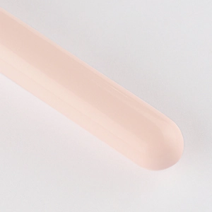 Detail of a pink flat-top foundation brush handle with glossy finish and rounded edge