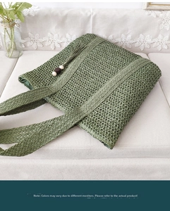 Detail of green straw tote bag with tassels and wooden beads on a white sofa