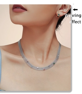Gros plan d'un mannequin portant collier en maille et créoles aux zircons colorés