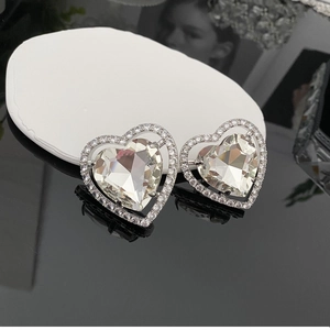 Détail d'une boucle d'oreille cœur en argent avec cristal central et entourage zircon