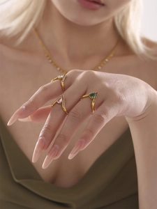 Détail de trois bagues dorées en V avec pierres multicolores en forme de poire et zircons