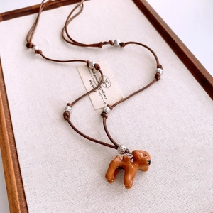 Détail du collier ajustable en cordon marron avec pendentif chien et perles métalliques