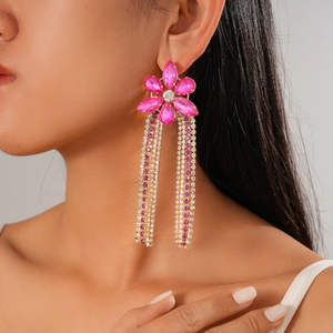 Gros plan de boucles d'oreilles fleur rose avec pompons et cristaux sur un mannequin