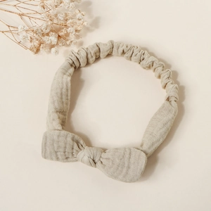 Macro detail of beige cotton baby headband with bow and elastic texture