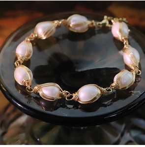 Macro shot of gold wire wrapped freshwater pearls on a delicate beaded bracelet