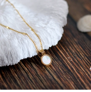 Macro view of French 18K gold plated titanium necklace with iridescent shell pendant detail