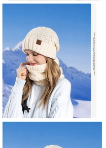 Detail of cream cable-knit hat and neck warmer set against a scenic snow mountain