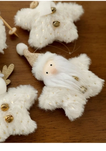 Macro detail of white plush star Christmas tree ornaments with golden bell accents