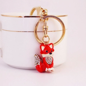 Charming red fox keychain with sparkling crystals and metal accents on a white dish