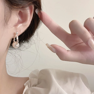Elegant geometric silver bead and white pearl hoop earrings shown on model