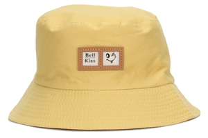 Close-up of a yellow bucket hat featuring a leather patch with a wink smiley face icon