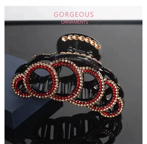 Close-up of large rhinestone hair claw with interlocking circles and red crystals