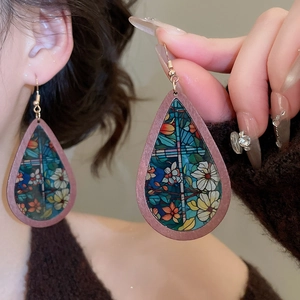 Close-up of model wearing ethnic wood teardrop earrings with floral glass pattern