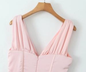 Détail d'une robe rose satinée sans manches avec décolleté en V et texture plissée élégante
