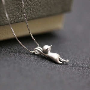 Macro detail of a matte cat pendant with brushed texture on a fine box chain necklace
