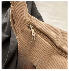 Detail of smooth metal zipper on beige corduroy bag with a white cloud charm pendant