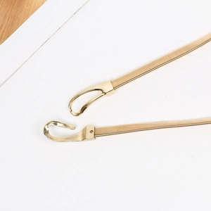 Detailed close-up of a gold metal elastic spring belt buckle showing the interlocking design