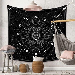 Detail of bohemian black moon phase and sun face tapestry hanging in a cozy living room