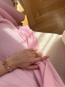 Close-up of luxury gold geometric ring and pink enamel H-clasp bracelet on wrist