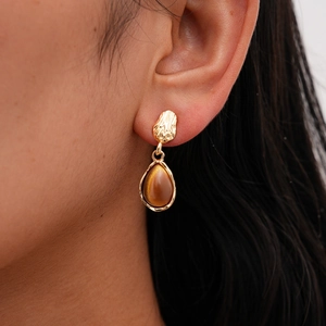Detail of vintage teardrop earrings with golden metal and brown resin stone on model