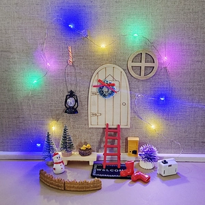 Miniature Christmas dollhouse scene with wooden door, LED string lights and accessories