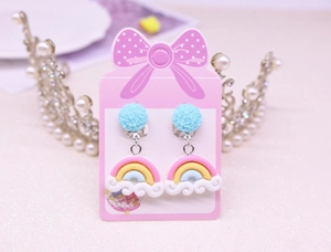 Detail of blue glitter beads and rainbow cloud clip-on earrings for kids on a pink card