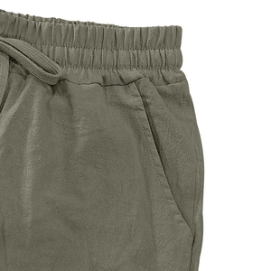 Detail of army green linen pants showing elastic drawstring waist and side pocket texture